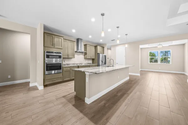 a large kitchen with kitchen island a sink dishwasher a stove a refrigerator and white cabinets with wooden floor