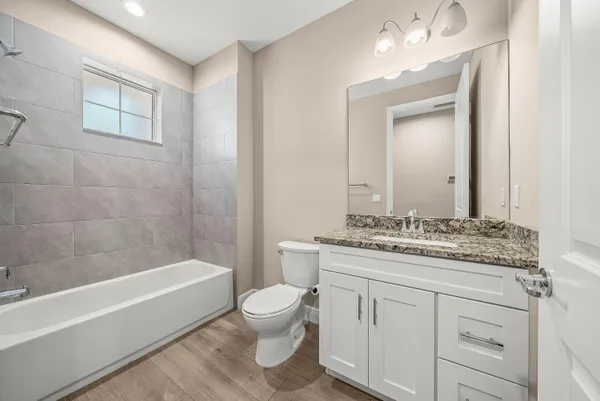 a bathroom with a granite countertop sink a toilet mirror and bathtub