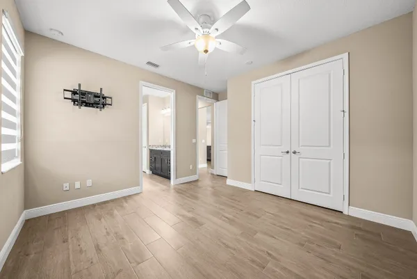 an empty room with wooden floor and a ceiling fan