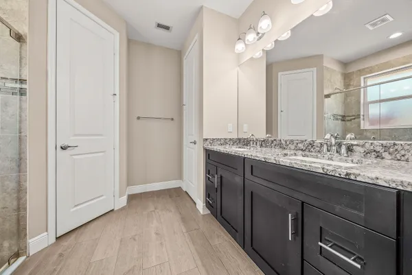a bathroom with a granite countertop double vanity sink and a mirror