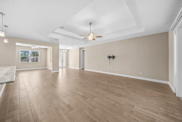an empty room with wooden floor chandelier and windows
