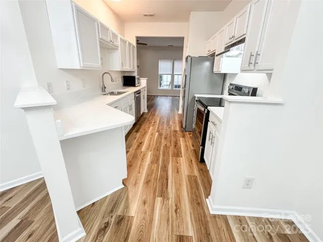 a kitchen with white cabinets sink and stove