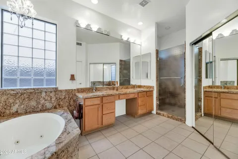 a bathroom with a granite countertop bathtub a sink and a large mirror