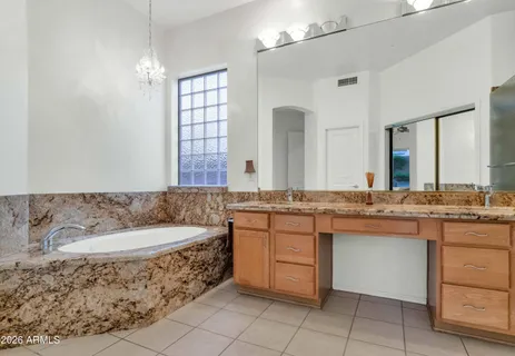 a bathroom with a granite countertop tub sink and mirror