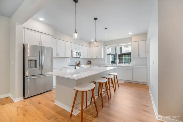a kitchen with kitchen island white cabinets and stainless steel appliances