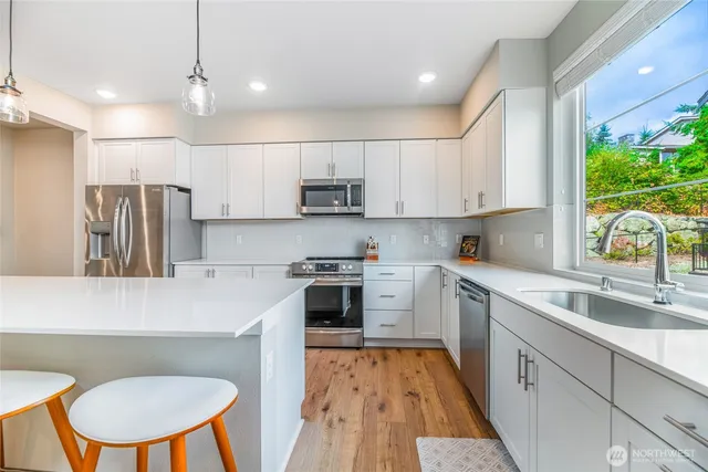 a kitchen with stainless steel appliances a refrigerator a sink a stove a table and chairs