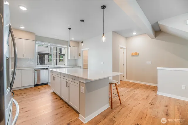 a large kitchen with stainless steel appliances kitchen island granite countertop a refrigerator a oven a sink and a wooden floors