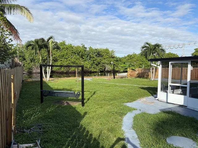a view of a garden with a bench in front of the house