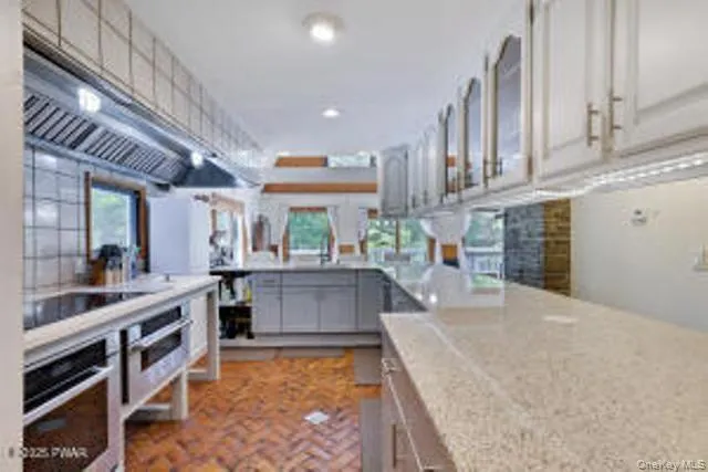 a large kitchen with stainless steel appliances a large counter top a stove and a sink