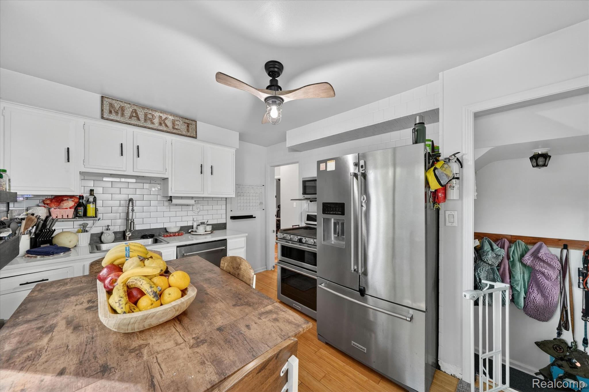 22729 Cleveland Street Dearborn, MI 48124 - Photo 10 of 32 Kitchen featuring stainless steel appliances, white subway tile backsplash, white cabinetry with dark hardware, and light-tone wood flooring