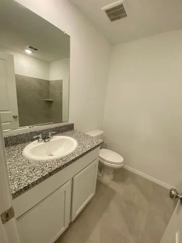 a bathroom with a granite countertop sink a toilet and a mirror