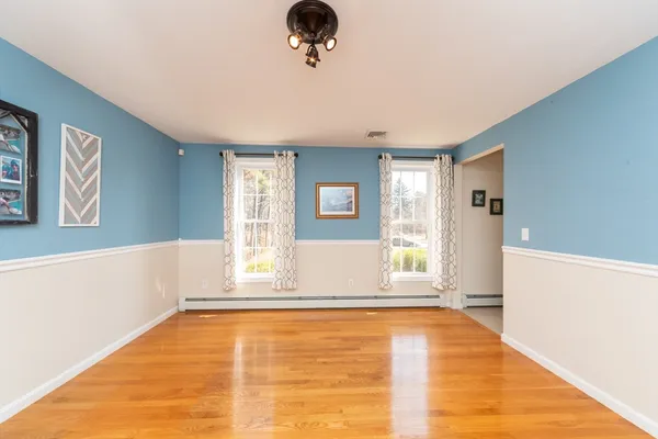 a view of an empty room with window and wooden floor