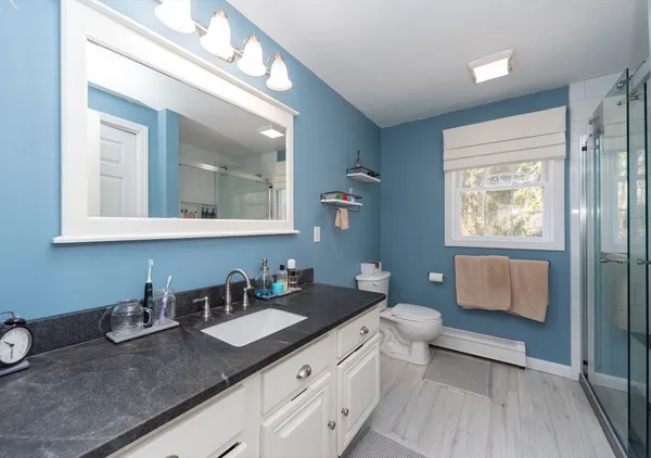 a bathroom with a granite countertop sink mirror vanity and toilet