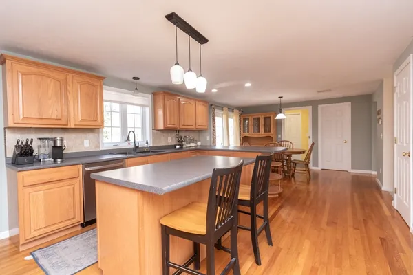 a kitchen with stainless steel appliances granite countertop a table chairs sink and cabinets