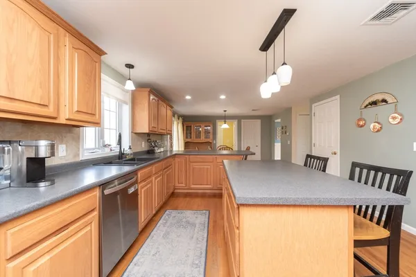 a kitchen with kitchen island a stove a sink a dining table and chairs with wooden floor