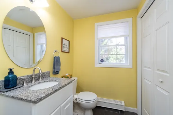 a bathroom with a granite countertop toilet sink and mirror