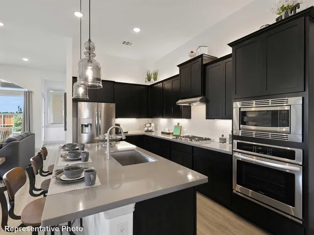 a kitchen with kitchen island stainless steel appliances a sink stove and refrigerator