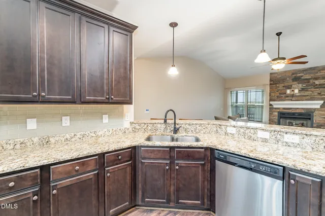 a kitchen with granite countertop a sink a counter space appliances and cabinets
