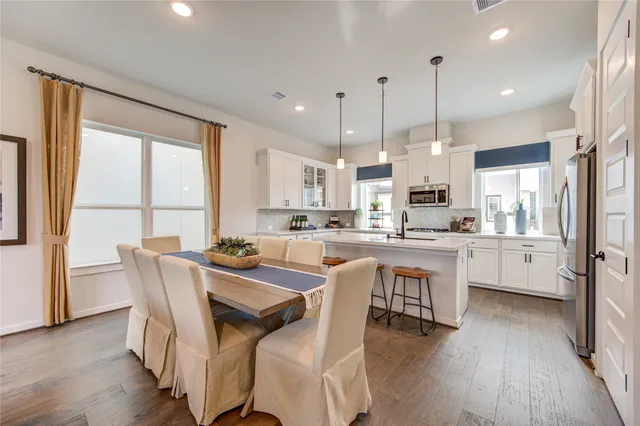 a view of a dining room and livingroom with furniture wooden floor kitchen view and a chandelier