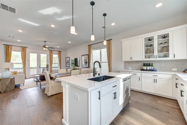 a large kitchen with kitchen island a sink a center island a stove and a wooden floor
