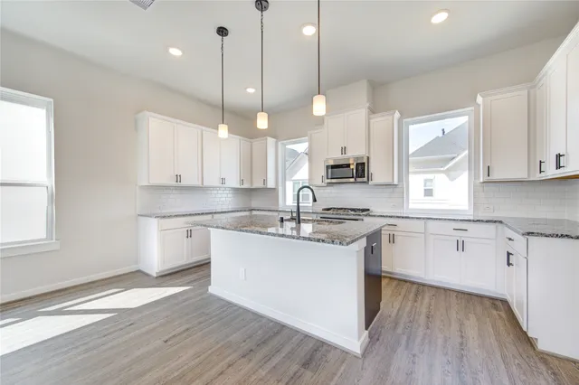 a kitchen with a sink wooden floor cabinets and a window