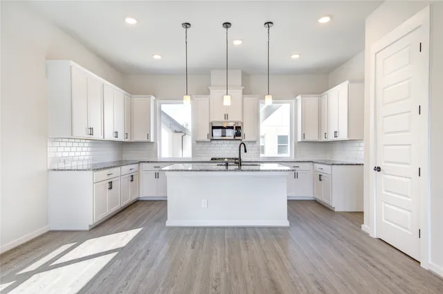 a large kitchen with a lot of counter space white cabinets and wooden floor