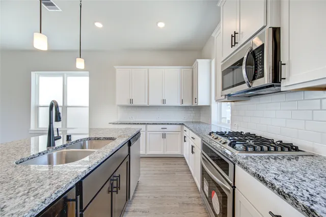 a kitchen with stainless steel appliances granite countertop a sink stove and microwave