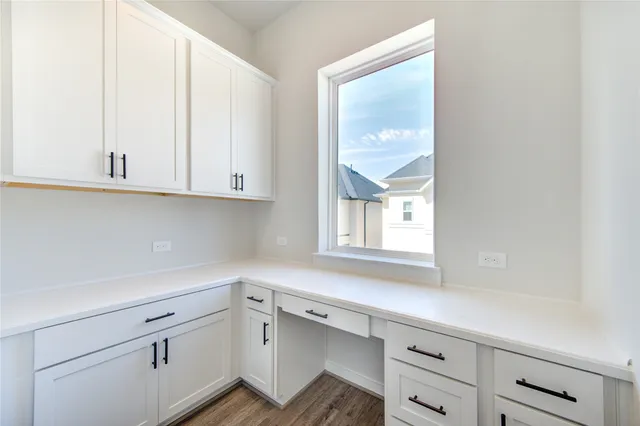a kitchen with white cabinets and a window