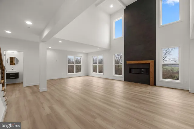 an empty room with wooden floor fireplace and windows