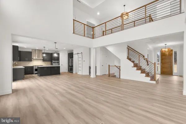 a view of an empty room and kitchen view with wooden floor