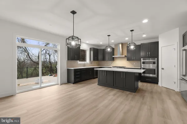 a large kitchen with a large counter top a sink stainless steel appliances and cabinets