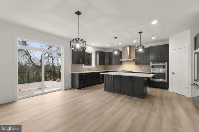 a large kitchen with a large counter top a sink stainless steel appliances and cabinets