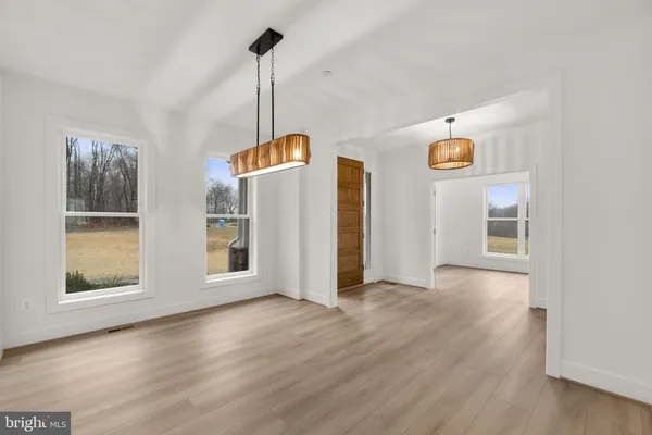 a view of an empty room with window and wooden floor