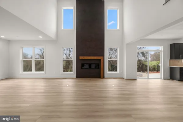 a view of an empty room with wooden floor and a fireplace