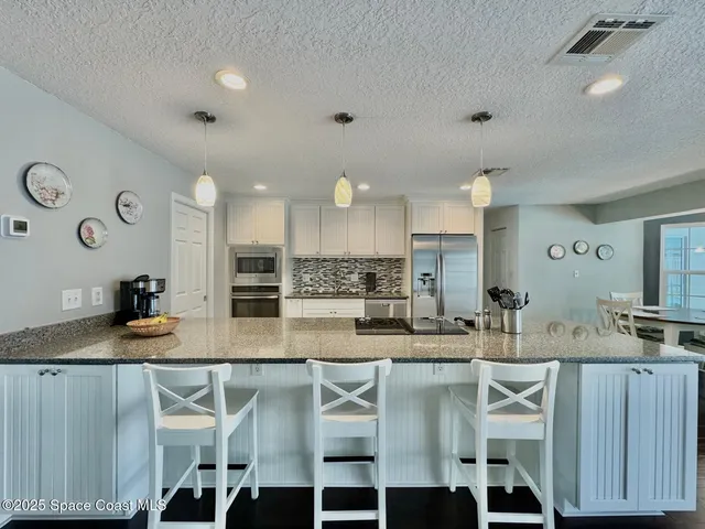 a kitchen with kitchen island granite countertop a table chairs sink and cabinets