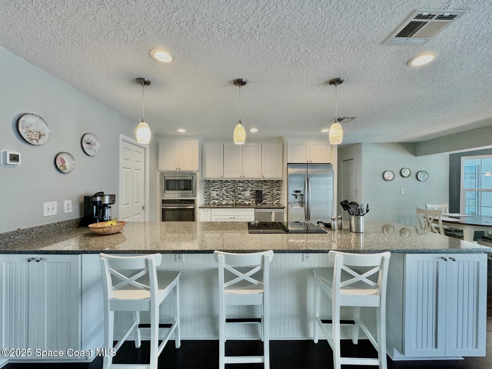 420 Rio Casa Drive North Indialantic, FL 32903 - Photo 13 of 49 a kitchen with kitchen island granite countertop a table chairs sink and cabinets