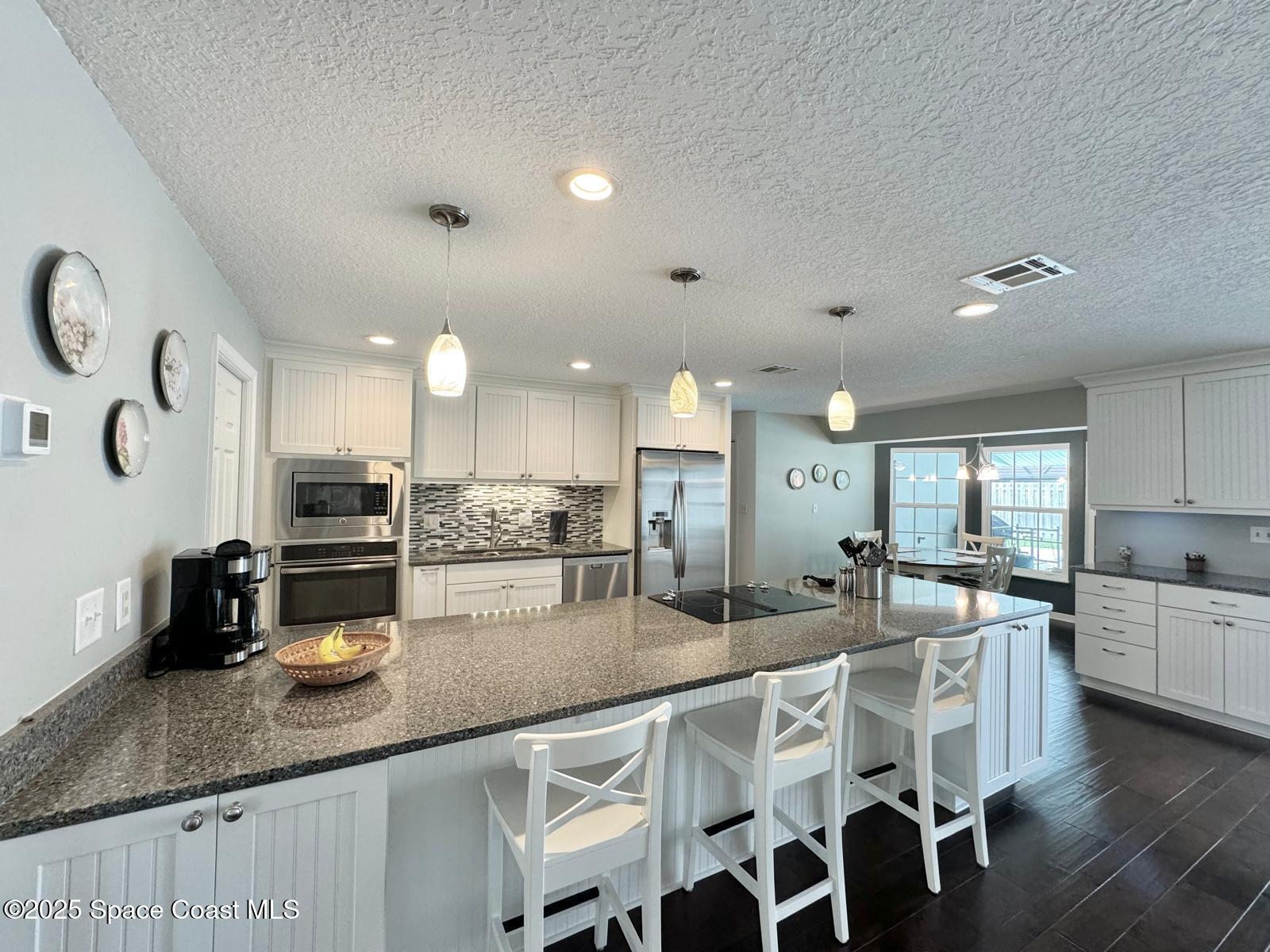 420 Rio Casa Drive North Indialantic, FL 32903 - Photo 14 of 49 a kitchen with stainless steel appliances granite countertop a sink a stove a dining table and chairs