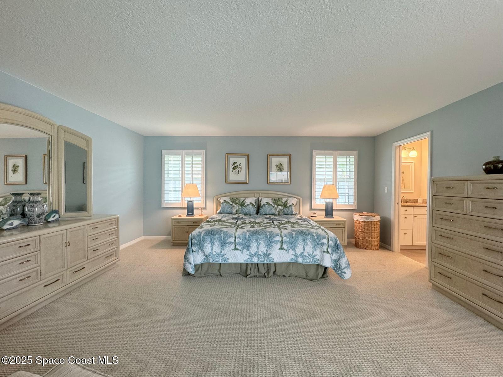 420 Rio Casa Drive North Indialantic, FL 32903 - Photo 35 of 49 a spacious bedroom with a large bed and a chandelier