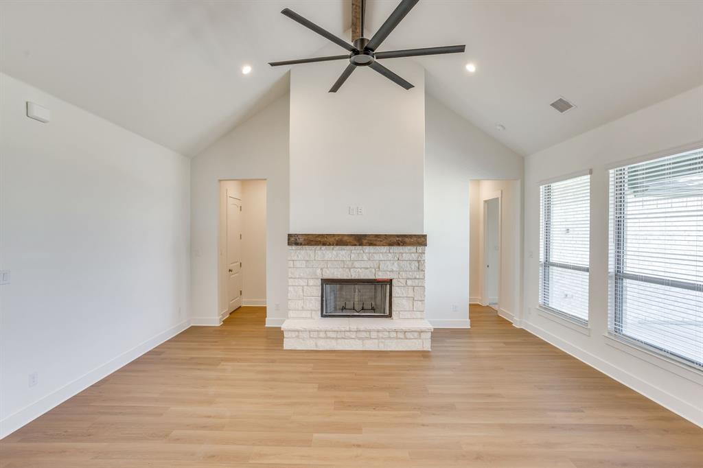 10611 Rye Bread Lane Venus, TX 76084 - Photo 10 of 36 Vaulted ceiling with a ceiling fan, stone-clad fireplace with a wood mantle, wood-finish flooring, and multiple windows