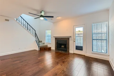 a view of an empty room with wooden floor a ceiling fan and windows