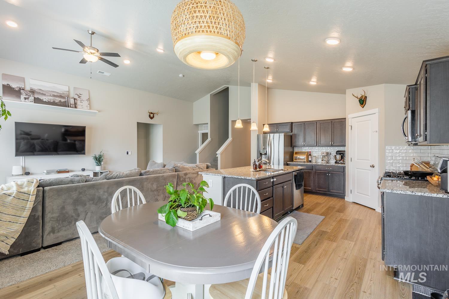 12623 Shadow Peak Street Caldwell, ID 83607 - Photo 24 of 50 Open-concept living space featuring wood-finish flooring, a kitchen with granite countertops and subway tile backsplash, a central island with pendant lighting, and recessed ceiling lights throughout