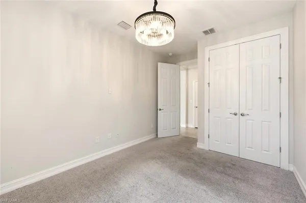 an empty room with chandelier fan and windows