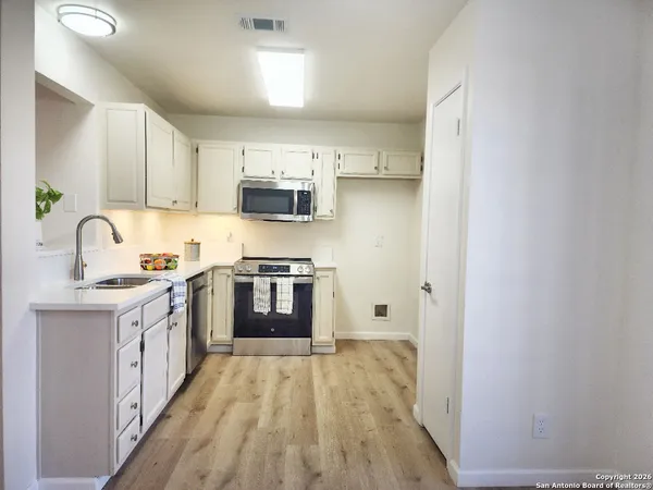 a kitchen with kitchen island granite countertop a sink cabinets and stainless steel appliances