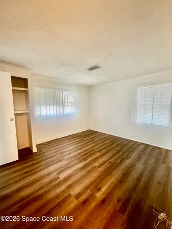 a view of empty room with wooden floor and fan
