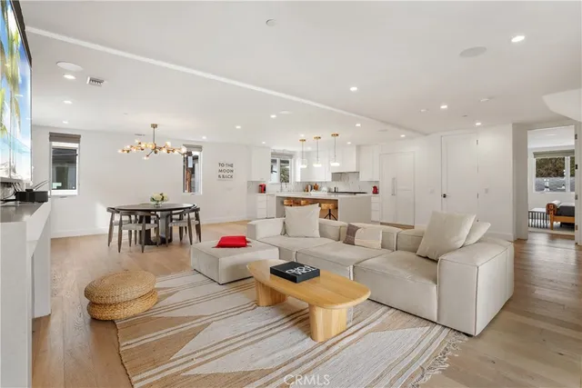 a living room with lots of furniture kitchen view and a wooden floor