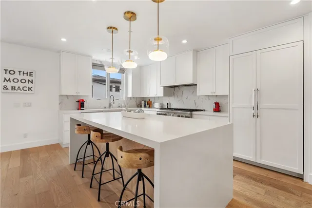 a kitchen with stainless steel appliances kitchen island a table chairs in it and white cabinets