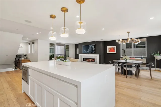 a large kitchen with kitchen island a island a stove a sink a dining table and chairs with wooden floor
