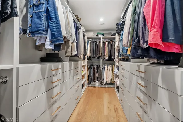 a view of walk in closet with clothes and shoes
