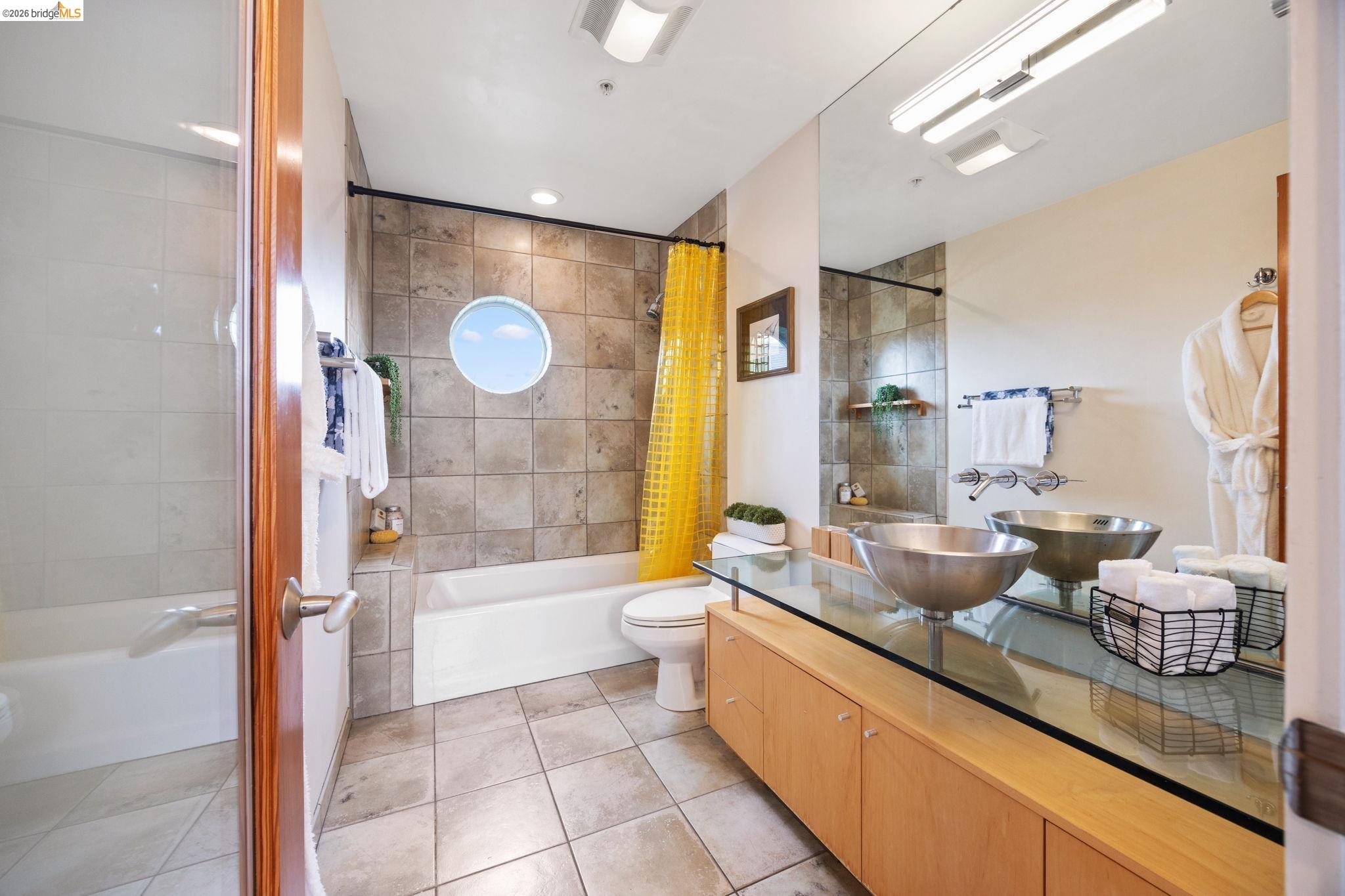 2709 Tenth Street, Unit D Berkeley, CA 94710 - Photo 18 of 29 Porcelain tub with tiled surround, circular window, and a separate shower enclosure