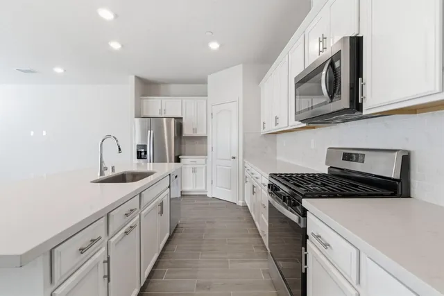 a kitchen with granite countertop white cabinets and stainless steel appliances